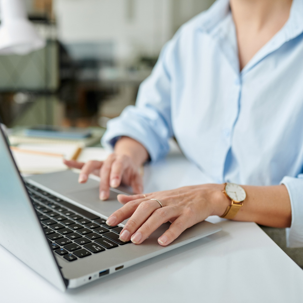 En kvinna sitter vid ett skrivbord och använder en bärbar dator.