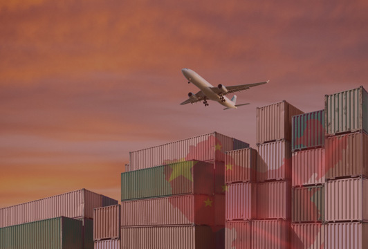 Ett plan som flyger över en stor stapel lastcontainrar.