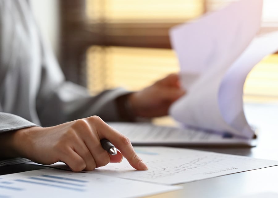 En person som sitter vid ett skrivbord med papper och penna.