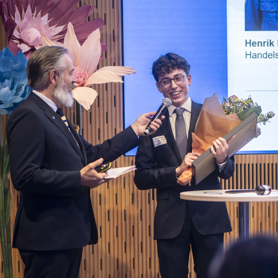 Tre män i kostym och slips håller i en blombukett.