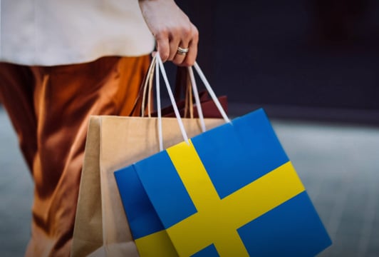 En person som bär shoppingkassar med den svenska flaggan.