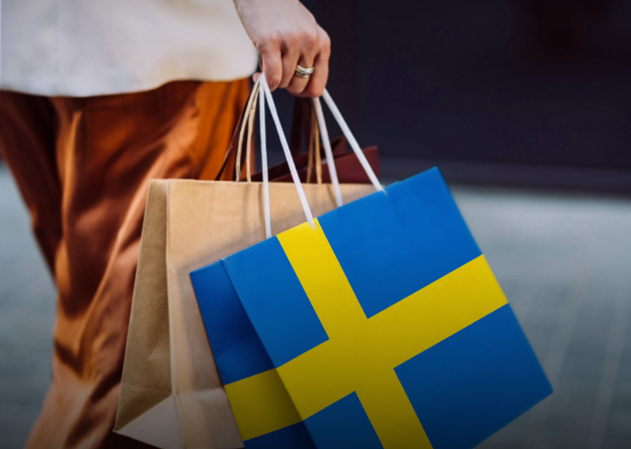 En person som bär shoppingkassar med den svenska flaggan.