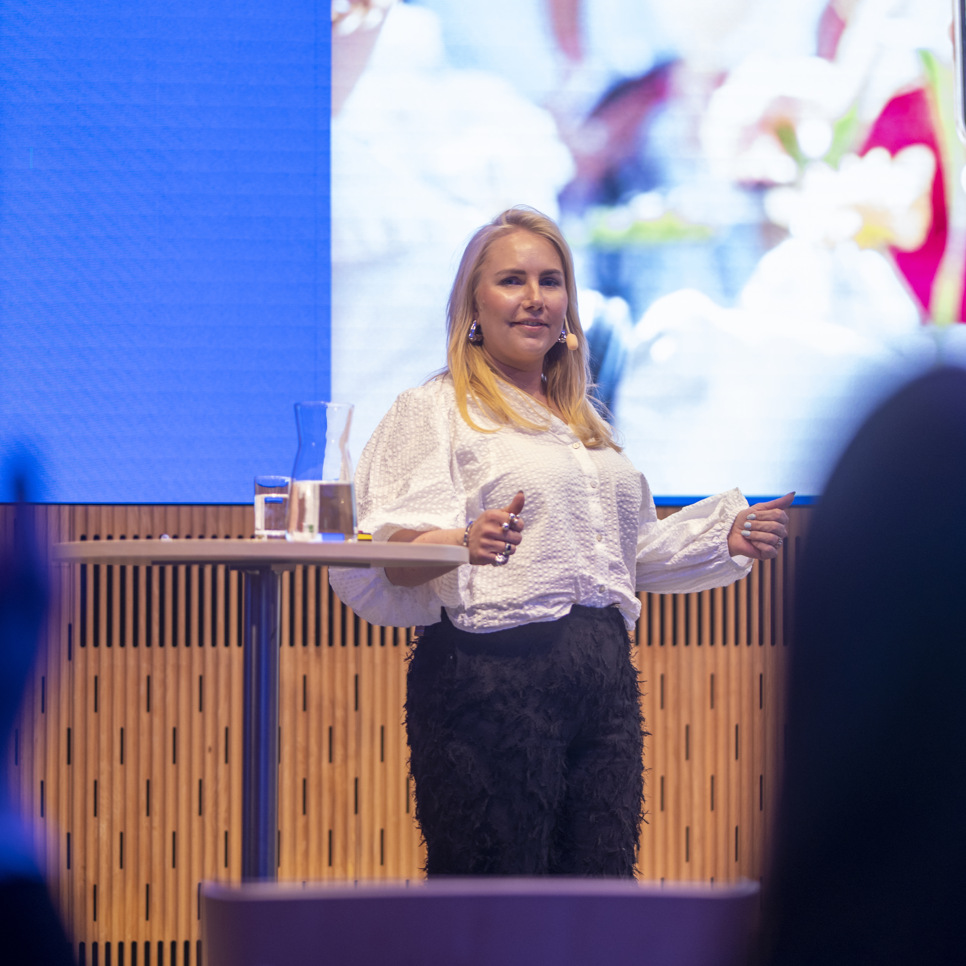 En kvinna står framför en skärm och håller en presentation.