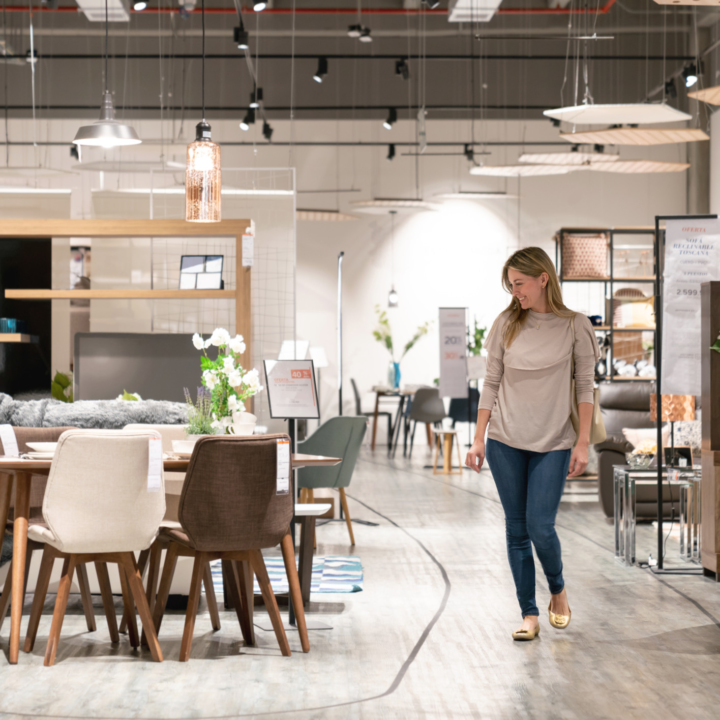 En kvinna som går genom en butik fylld med möbler.