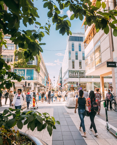 En grupp människor som går längs en gata bredvid höga byggnader.