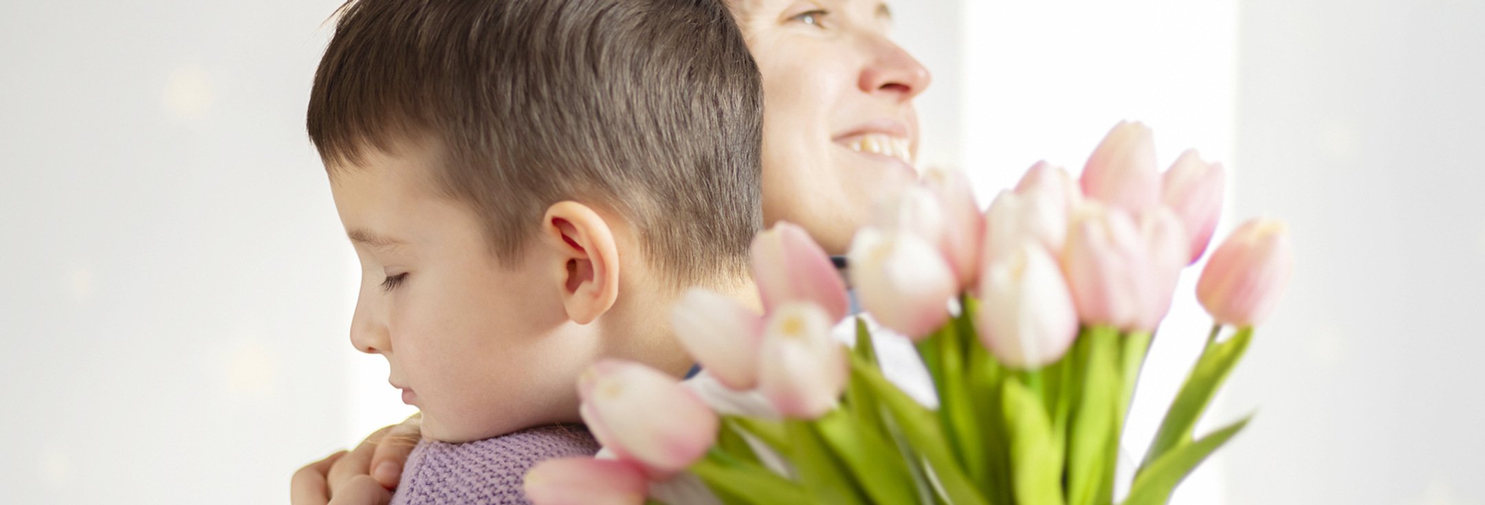 En kvinna håller ett barn och en bukett blommor.