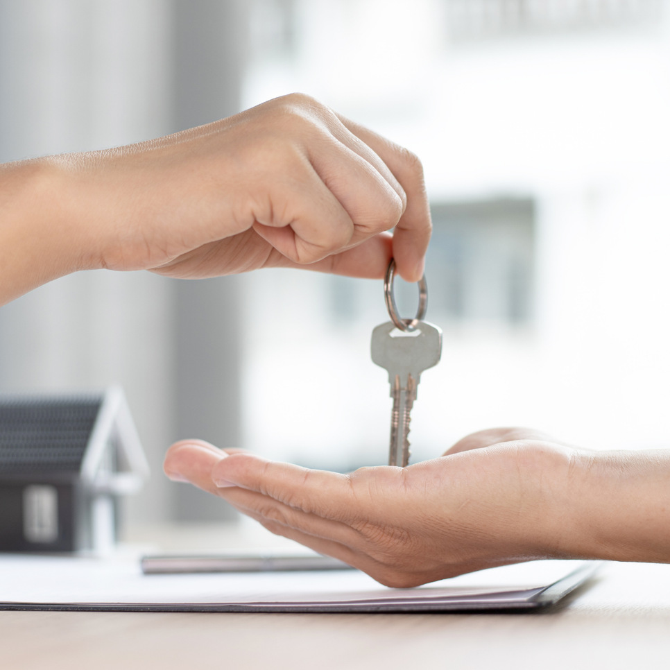 En person som överlämnar en husnyckel till en annan person.