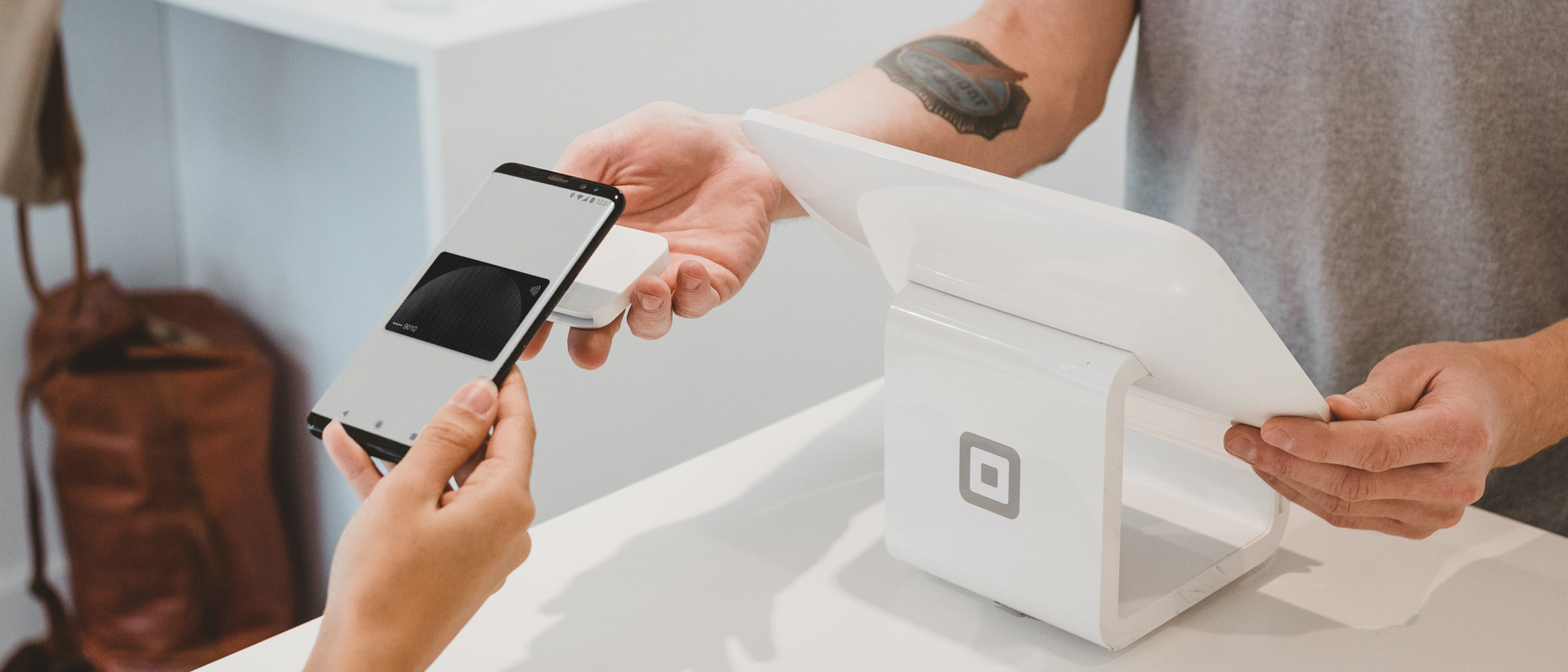 En man och en kvinna håller i en smart telefon vid ett bord.