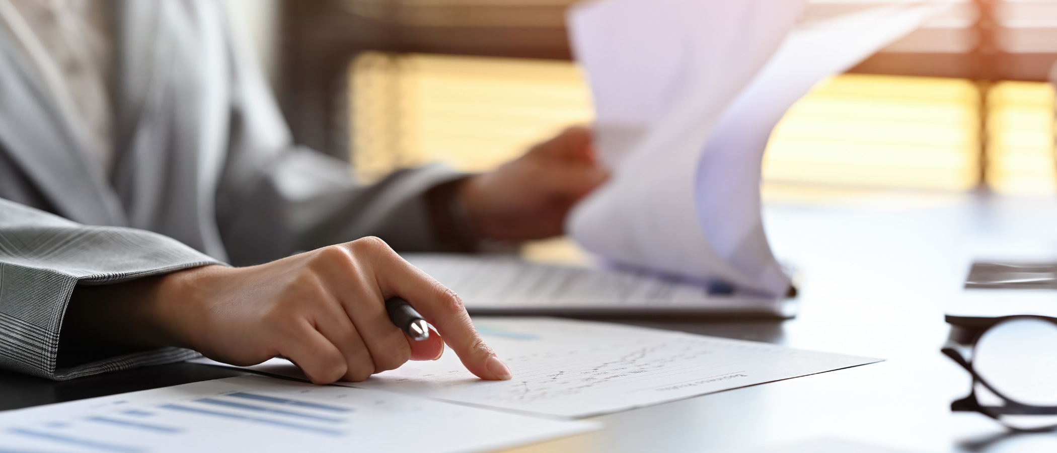 En person som sitter vid ett skrivbord med papper och penna.