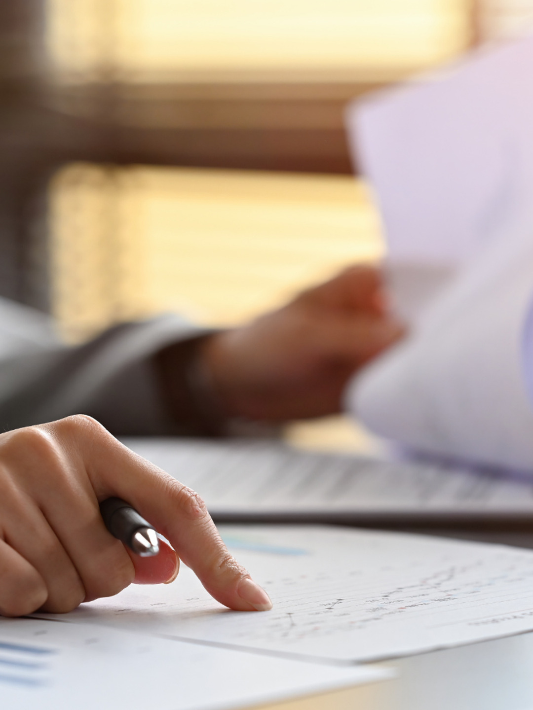 En person som sitter vid ett skrivbord med papper och penna.