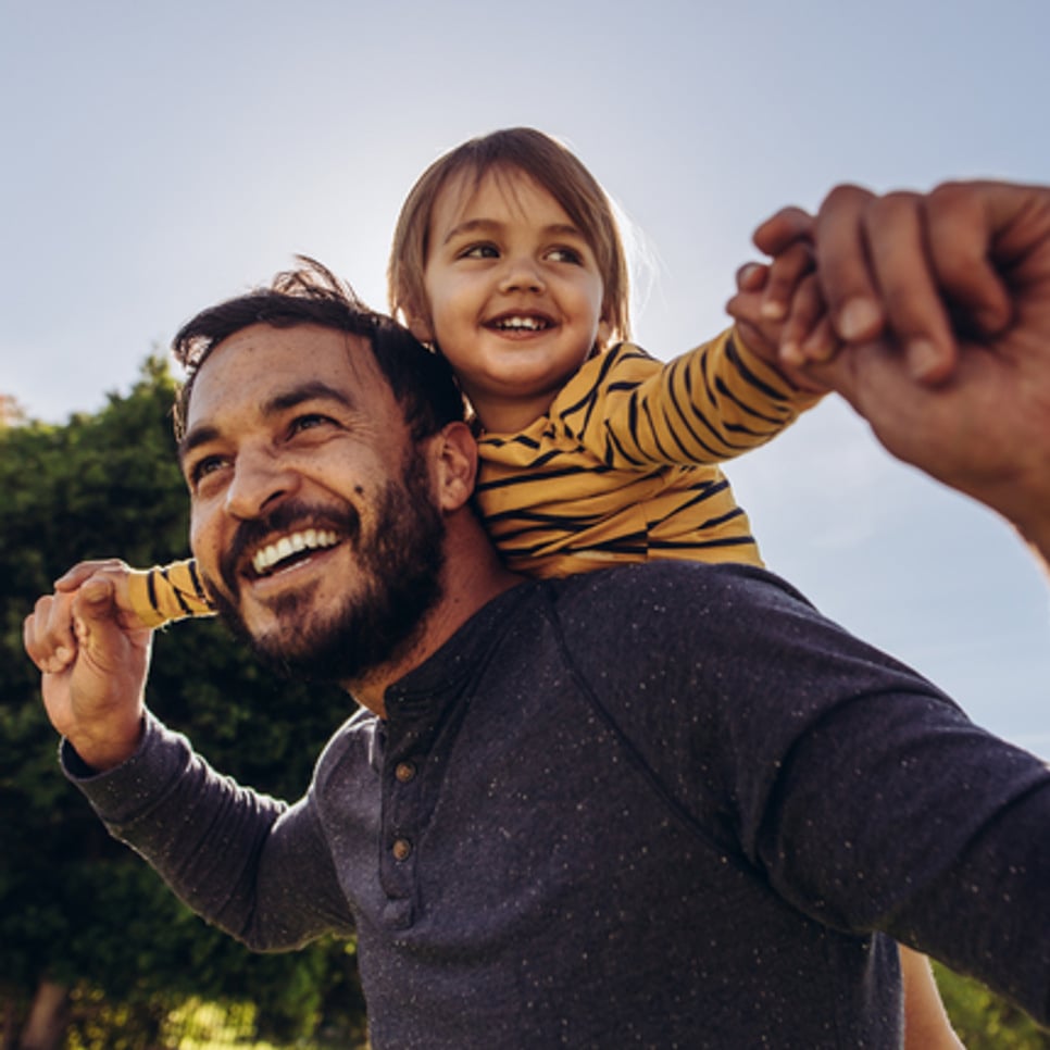 En man som håller en liten flicka på sina axlar.