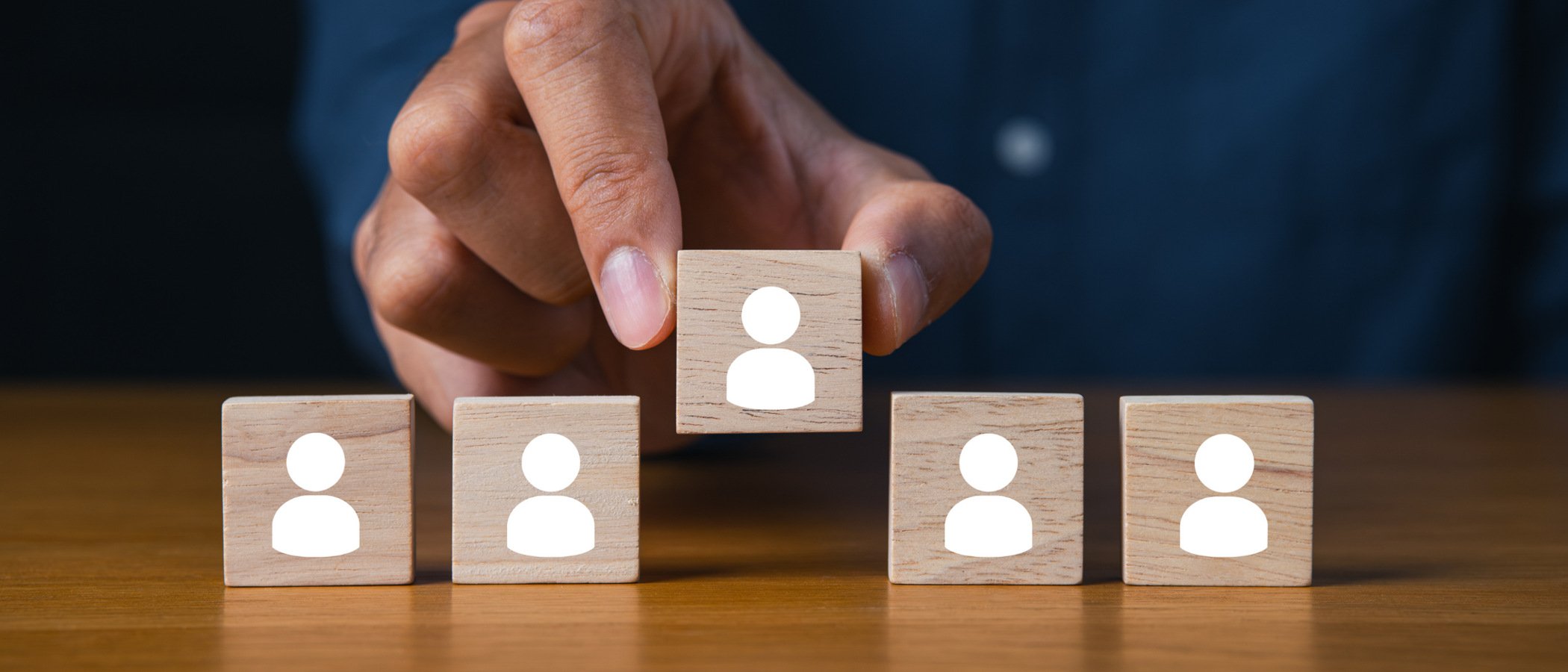 En person som placerar ett träblock med en grupp människor på.