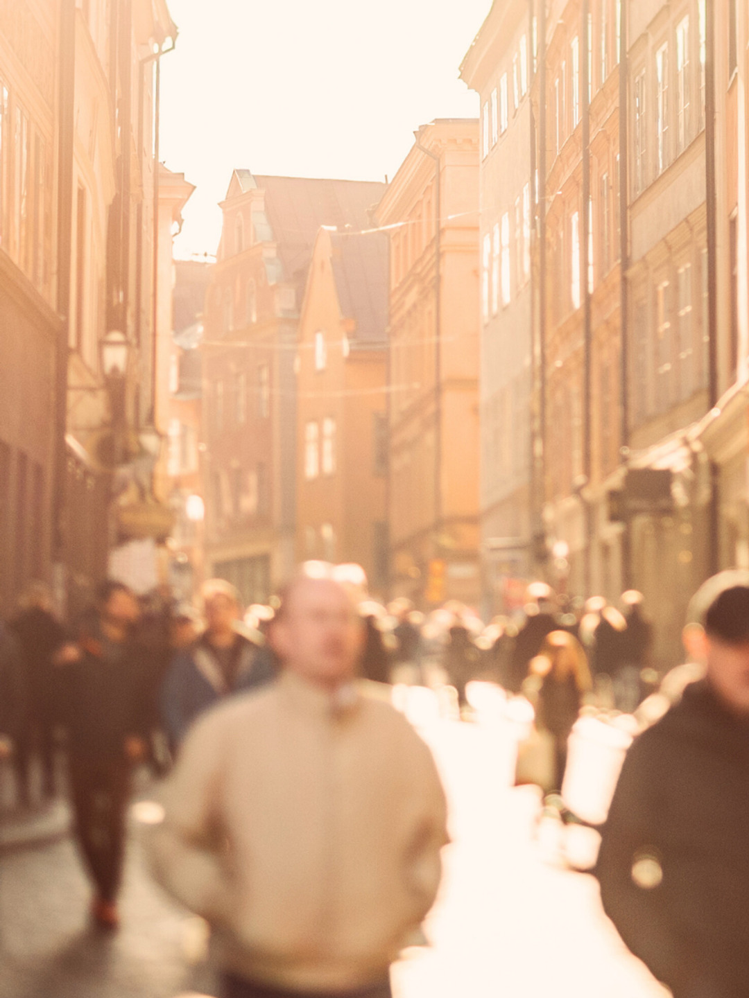 En grupp människor som går längs en gata bredvid höga byggnader.