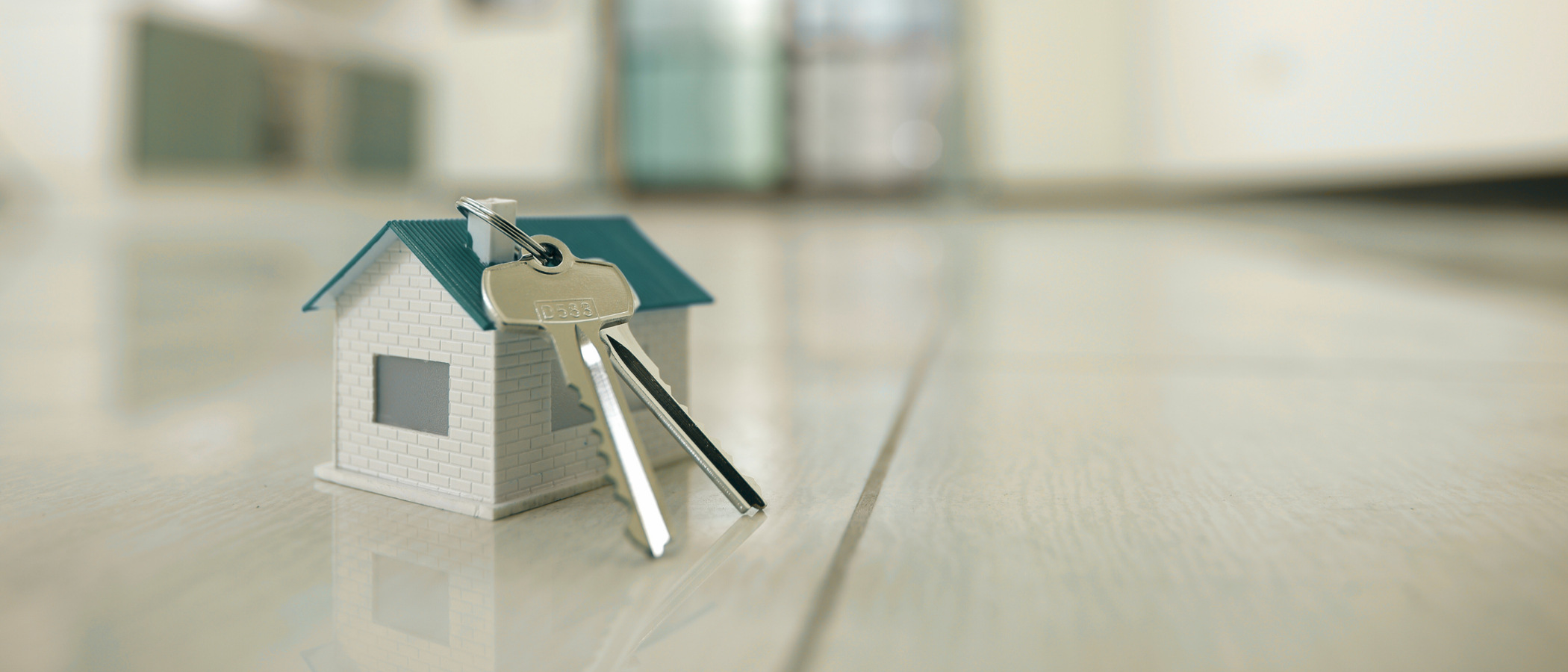 En nyckelring i form av ett hus som ligger på ett hårt trägolv.