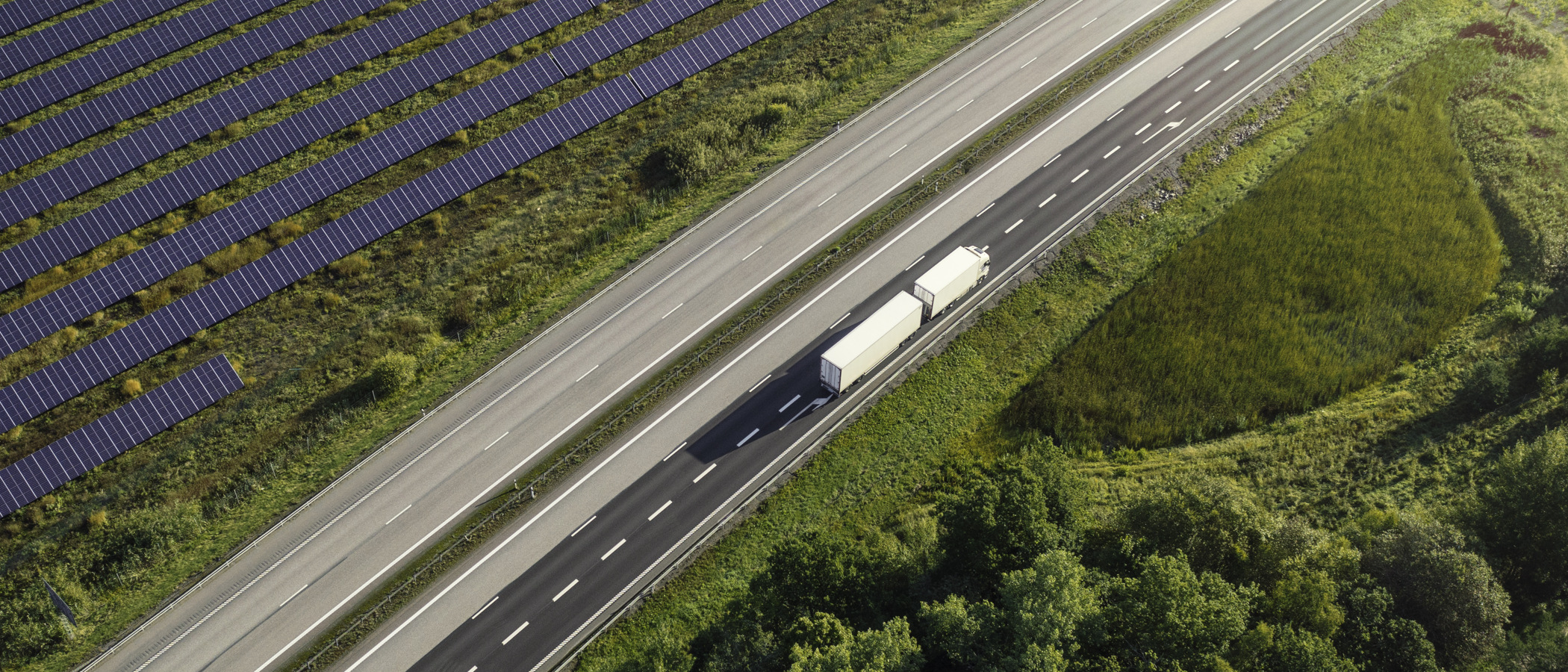 En lastbil som kör på en väg bredvid en skog.