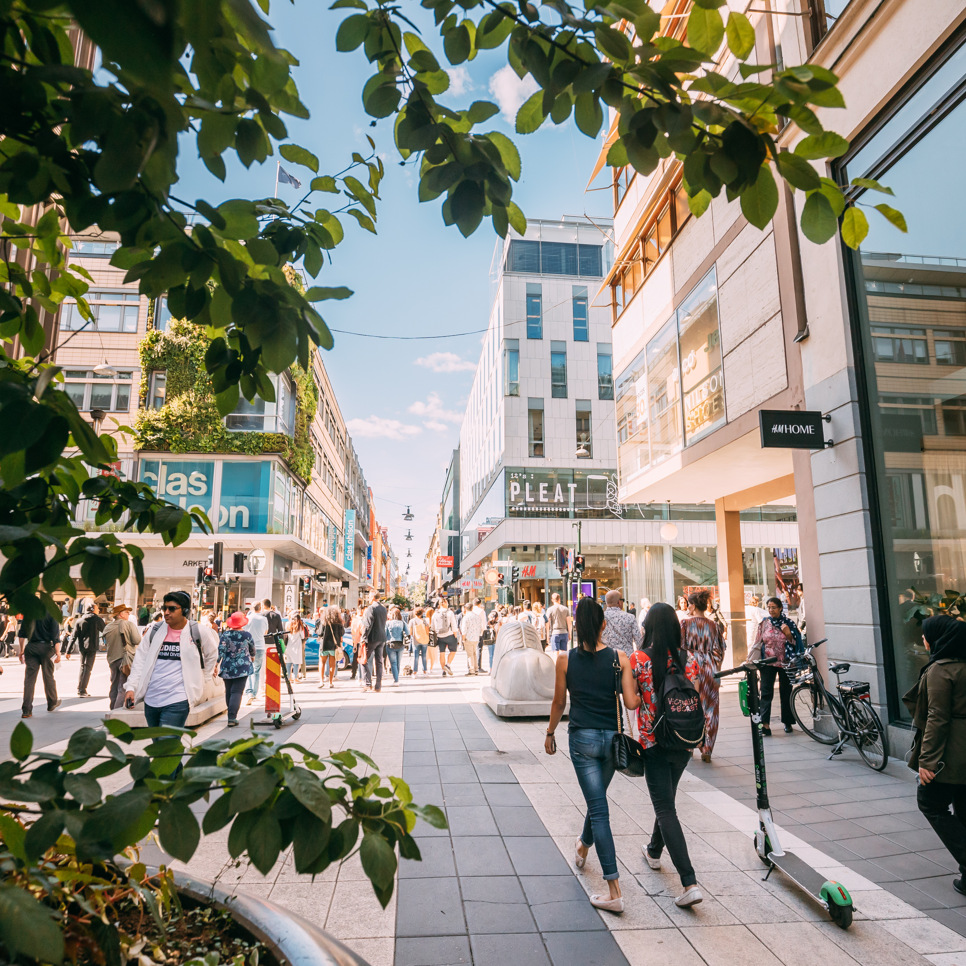 En grupp människor som går längs en gata bredvid höga byggnader.