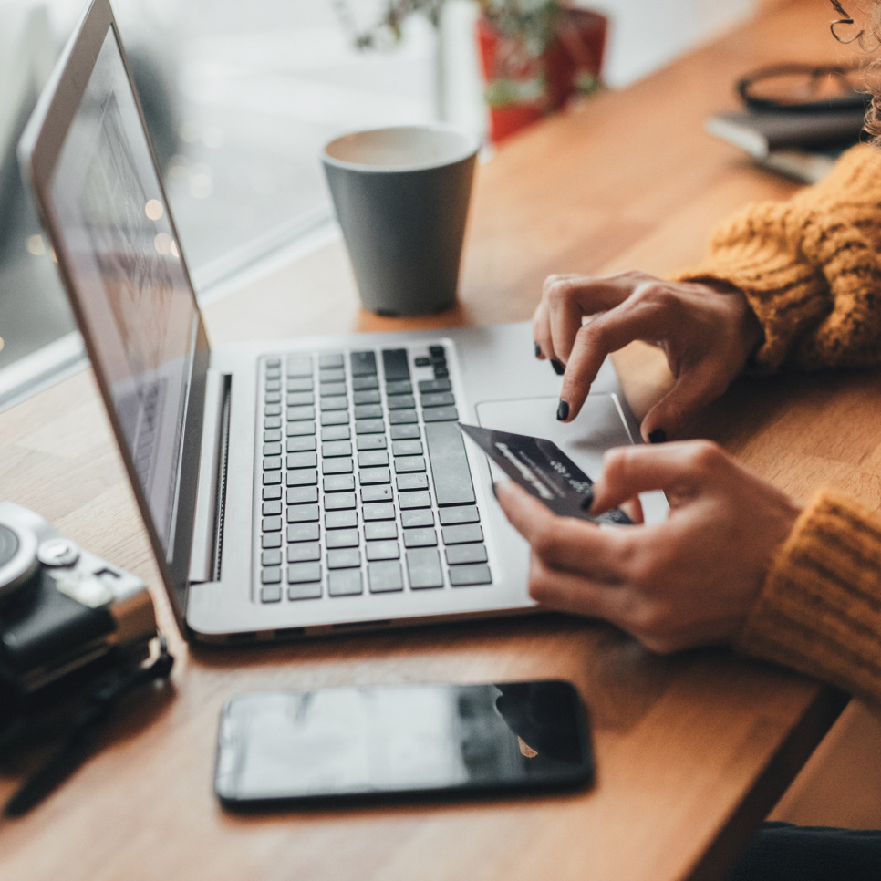 En kvinna sitter vid ett bord och använder en bärbar dator.