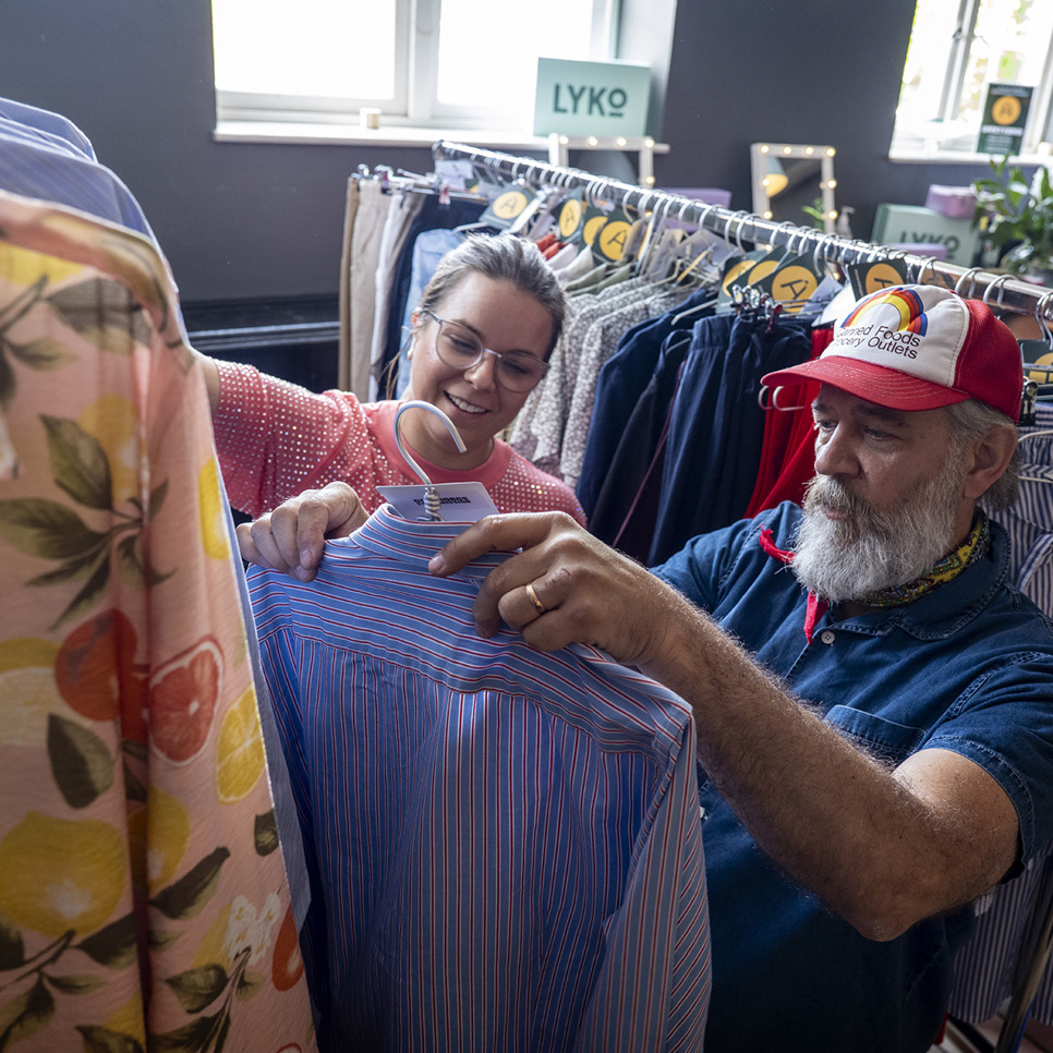 En man och en kvinna tittar på skjortor i en klädaffär.