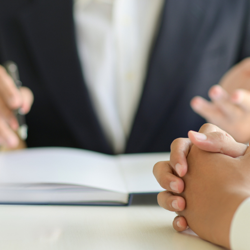 Två personer sitter vid ett bord med en bok och en penna.