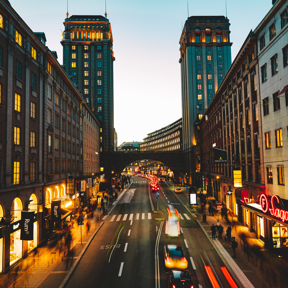 En livlig stadsgata på natten med höga byggnader.