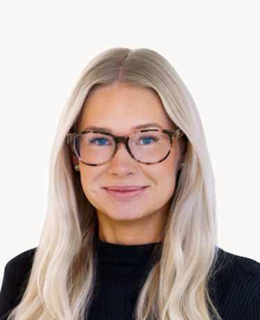 En kvinna med långt blont hår som bär glasögon.