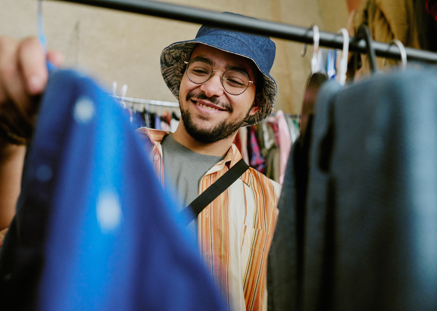 En man med hatt och glasögon tittar på en blå väska.