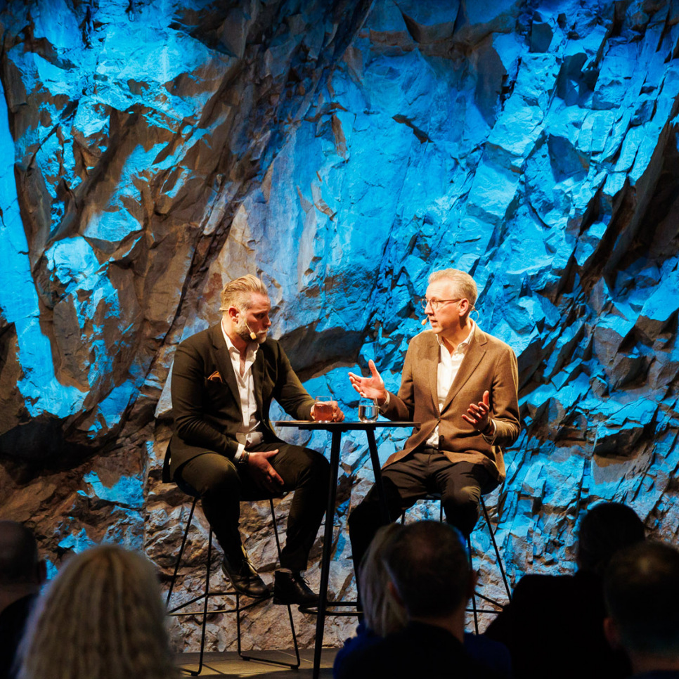 Några män som sitter bredvid varandra på en scen.