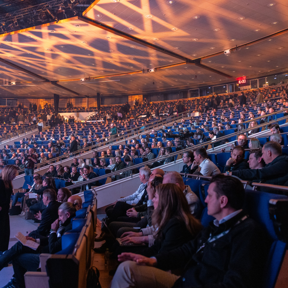 En folkmassa som sitter i ett stort auditorium.