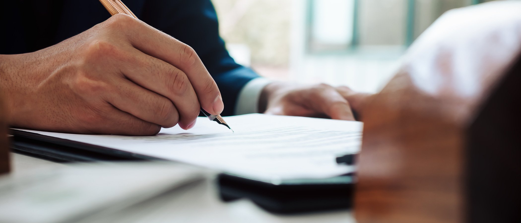 närbild på en person som skriver på ett dokument