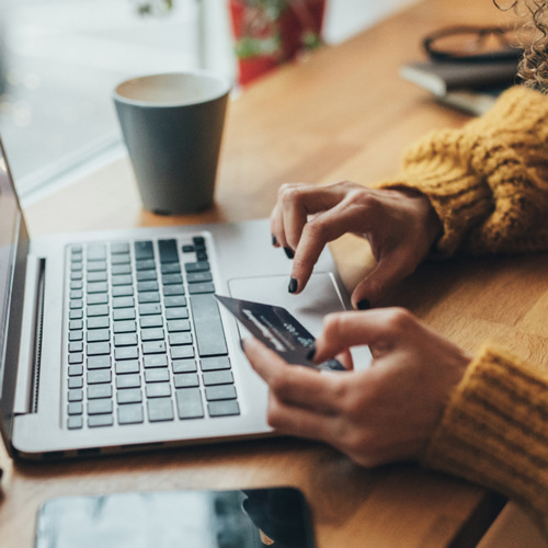 En kvinna sitter vid ett bord och använder en bärbar dator.