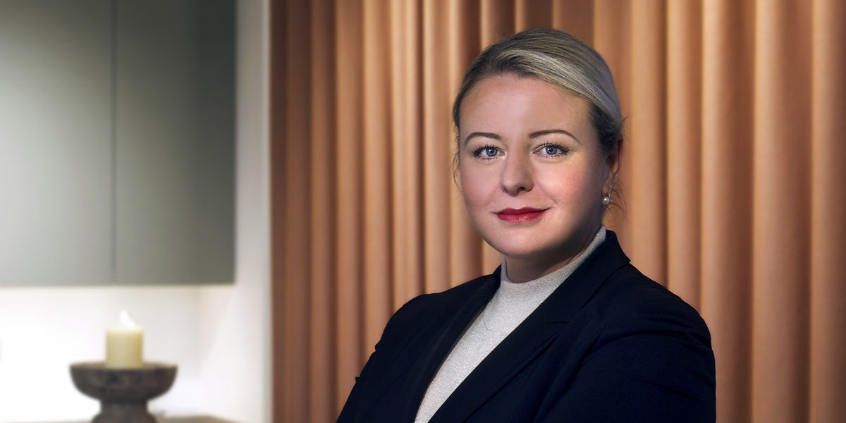En kvinna som st&aring;r framf&ouml;r en disk med ett stearinljus.