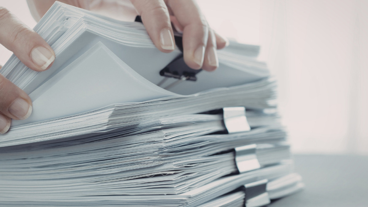 En person håller i en bunt papper.