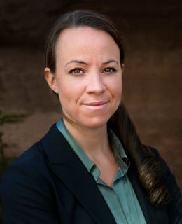 En kvinna i svart kavaj och grön skjorta.