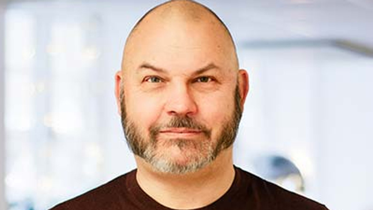 En man med skalligt huvud som bär en brun skjorta.