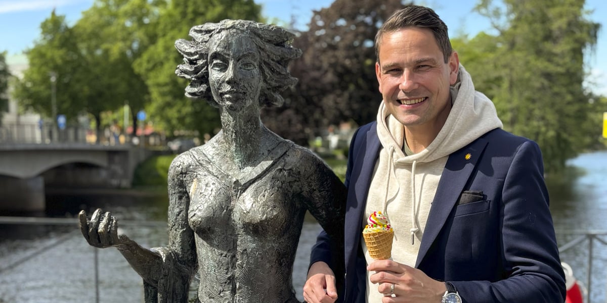 En man som står bredvid en staty av en kvinna.