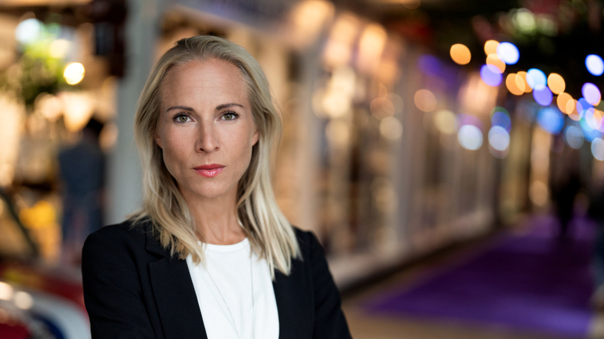 En kvinna med armarna i kors som står framför en bil.