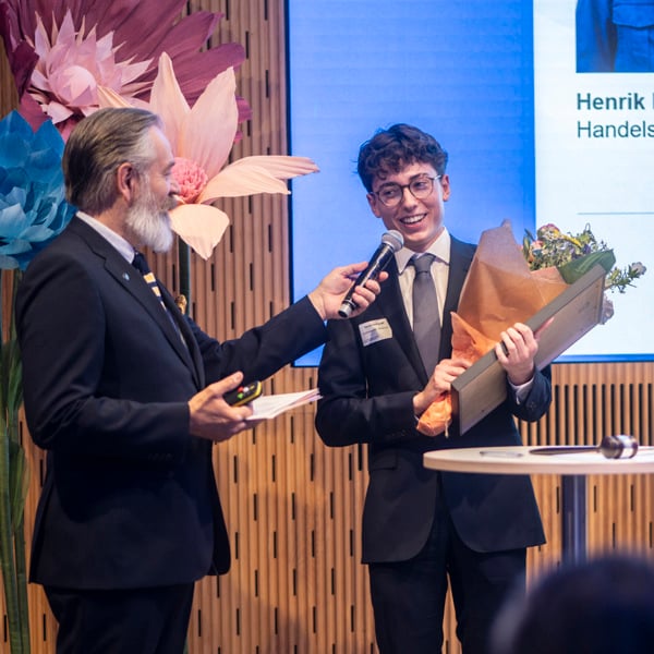 Tre män i kostym och slips håller i en blombukett.