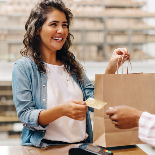 En kvinna håller i en shoppingväska och ett kreditkort.