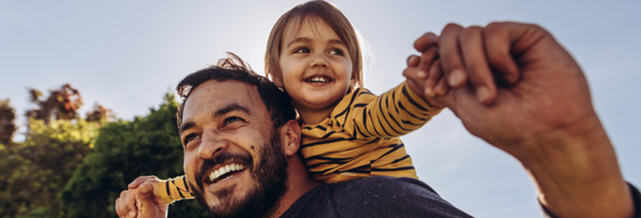 En man som håller en liten flicka på sina axlar.