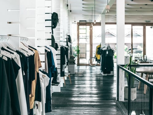 En rad kläder som hänger på en stång i en butik.