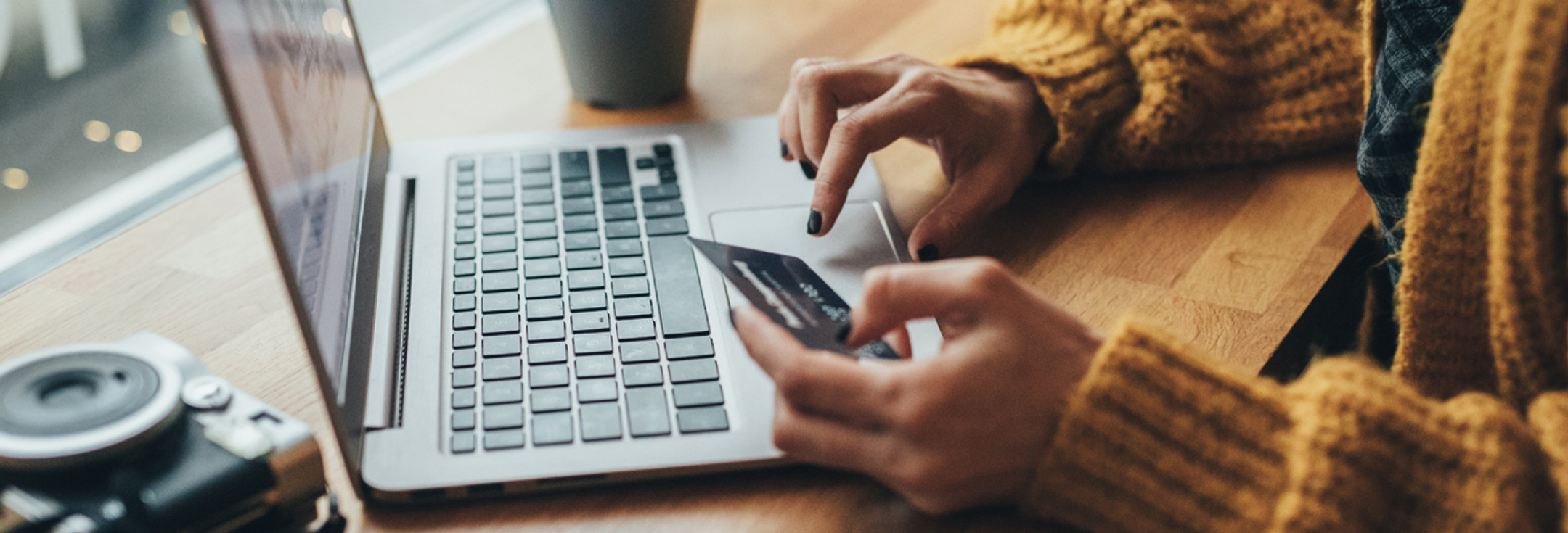 En kvinna sitter vid ett bord och använder en bärbar dator.