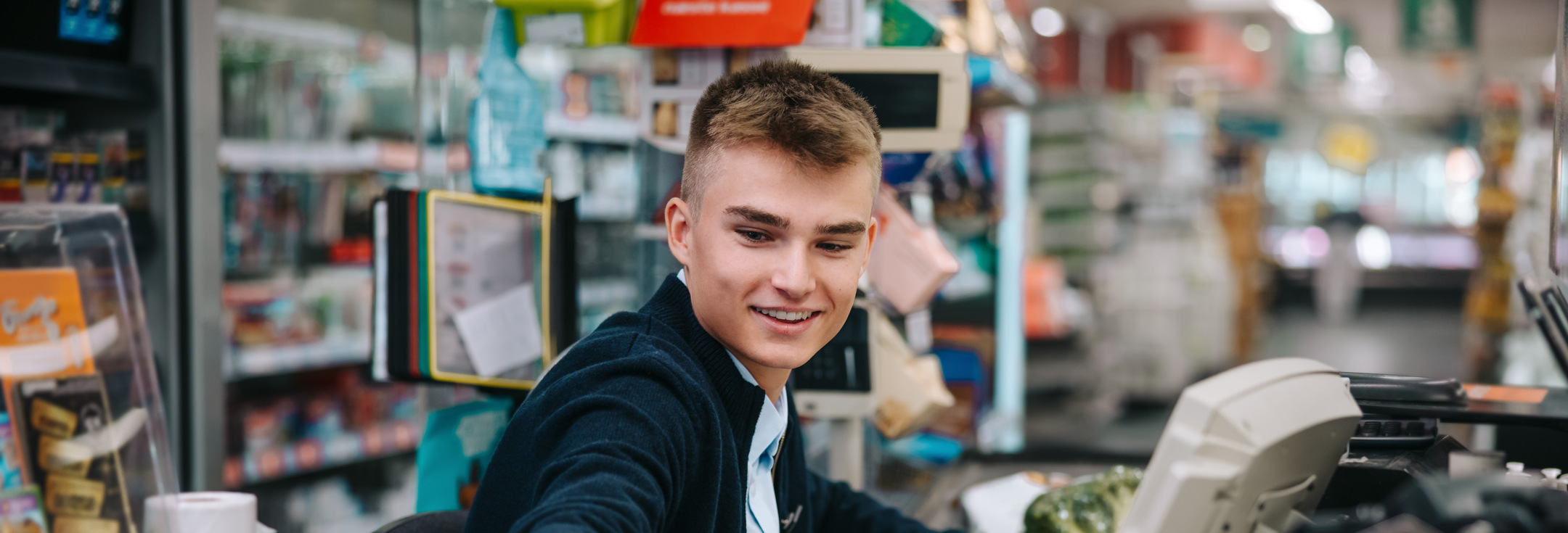 En man sitter vid en kassaapparat i en butik.