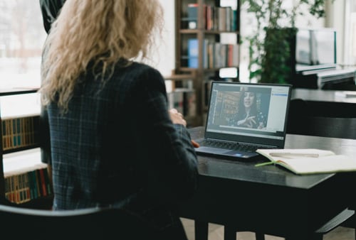 En kvinna sitter vid ett bord med en bärbar dator.