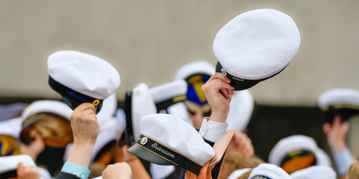 En grupp uniformsklädda personer som håller upp hattar.