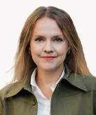 En kvinna klädd i en grön jacka och en vit skjorta.