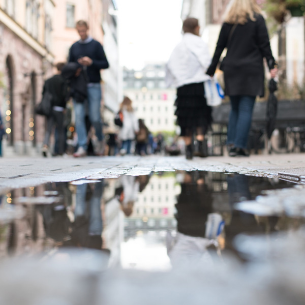 En grupp människor som går längs en gata bredvid en vattenpöl.