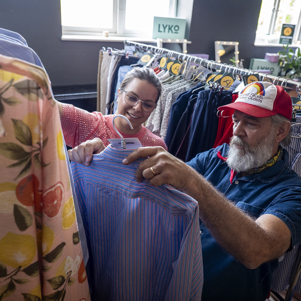 En man och en kvinna tittar på skjortor i en klädaffär.