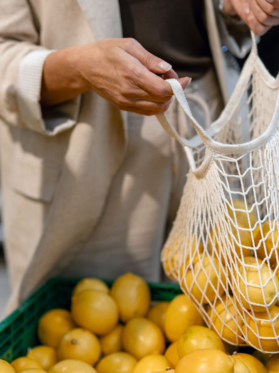 En person som håller en påse med frukt framför en hög med bananer.