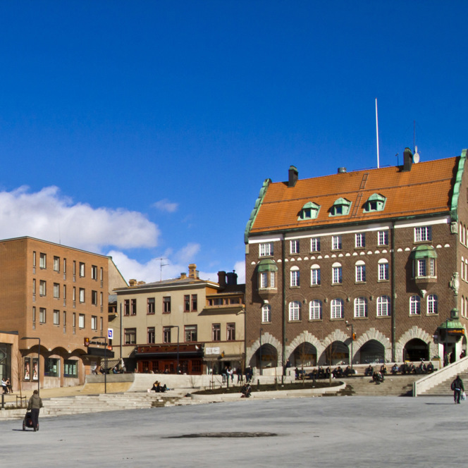 En man åker skateboard på en gata bredvid höga byggnader.
