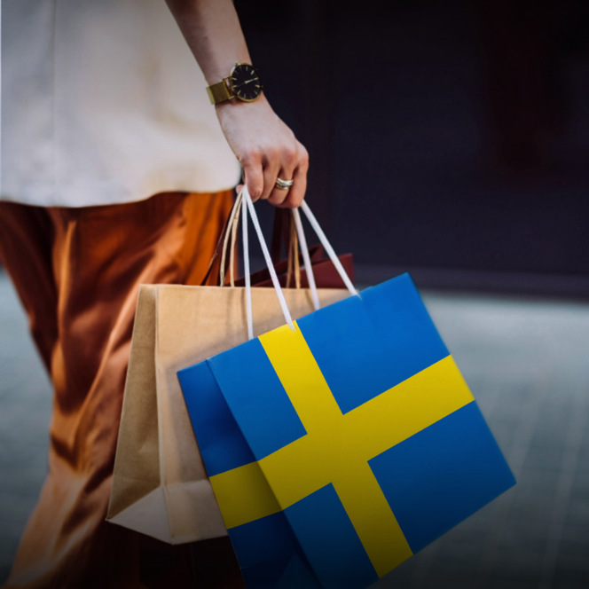 En person som bär shoppingkassar med den svenska flaggan.